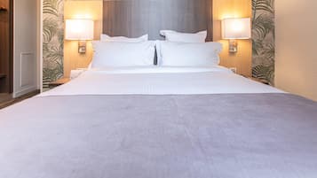 A hotel room with a large bed, two bedside lamps, and a headboard with a leaf pattern.