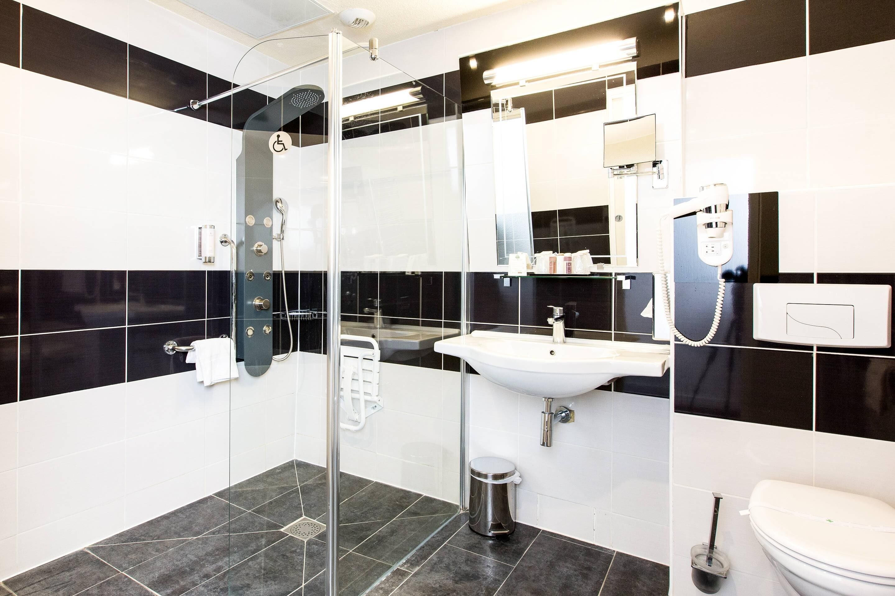 A modern bathroom with a glass shower enclosure, a white sink, and a toilet.
