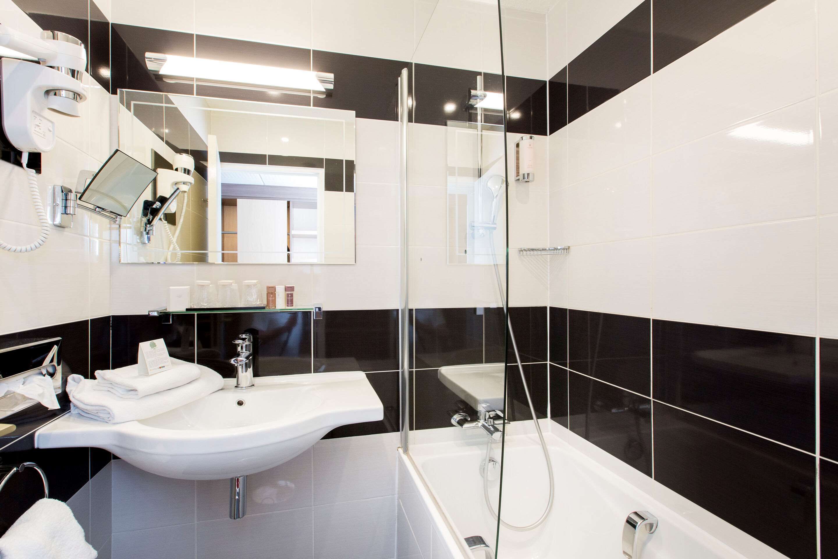A modern bathroom with a white sink, a glass-enclosed shower, and a large mirror.