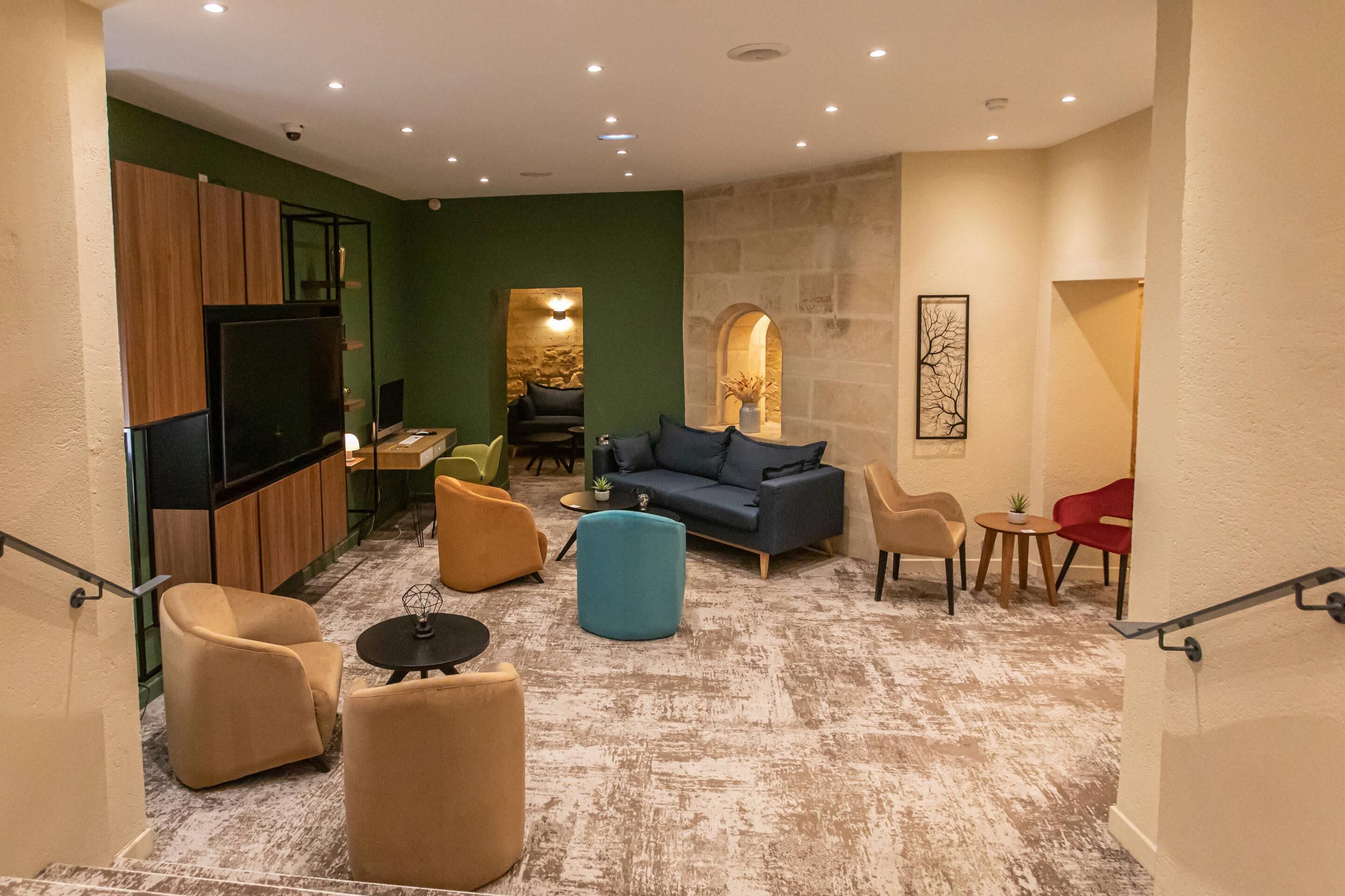 Un intérieur moderne avec un canapé, des fauteuils, un téléviseur et un mur en pierre.