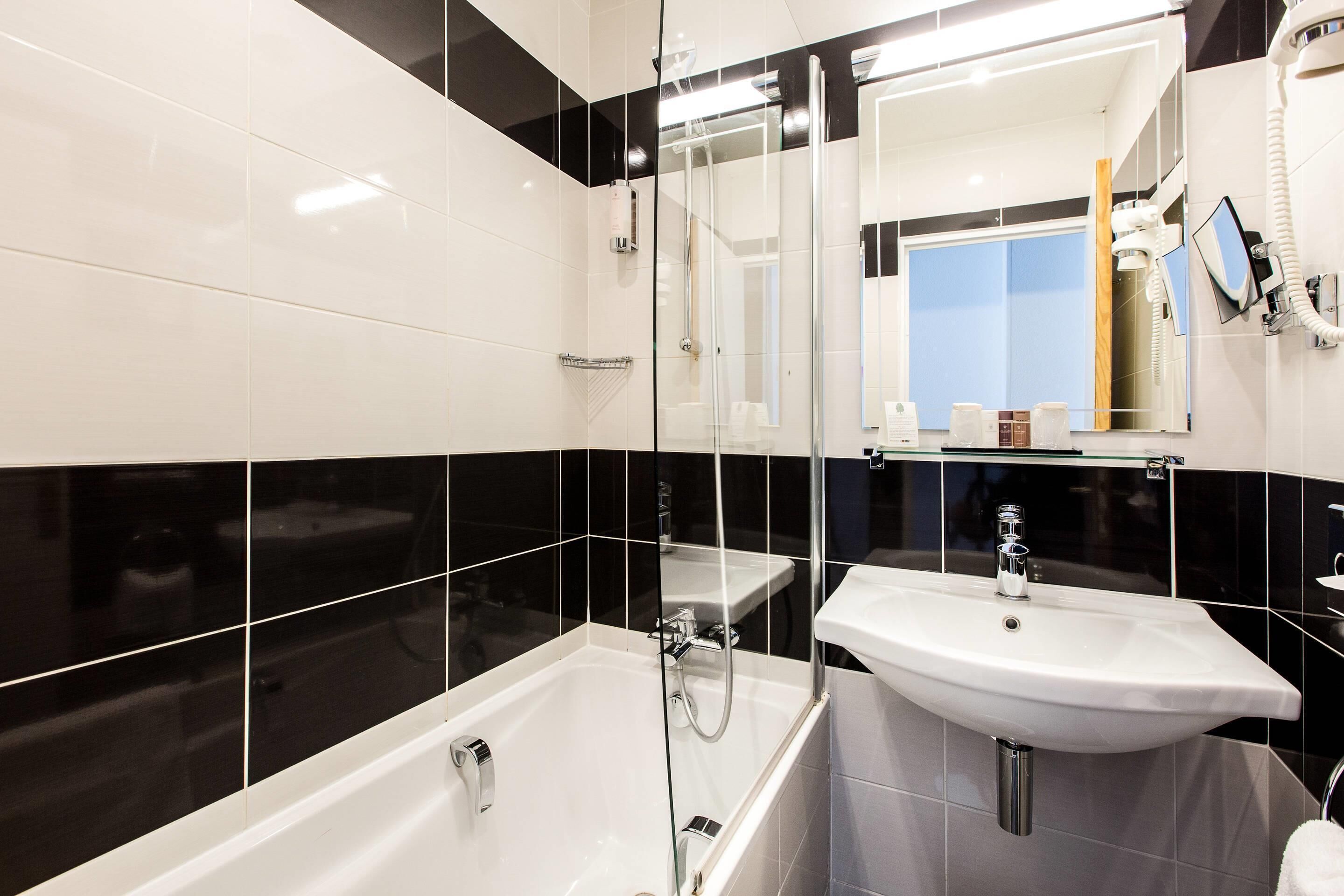 Une salle de bain moderne avec une douche à parois de verre, un lavabo blanc et un miroir au-dessus du lavabo.