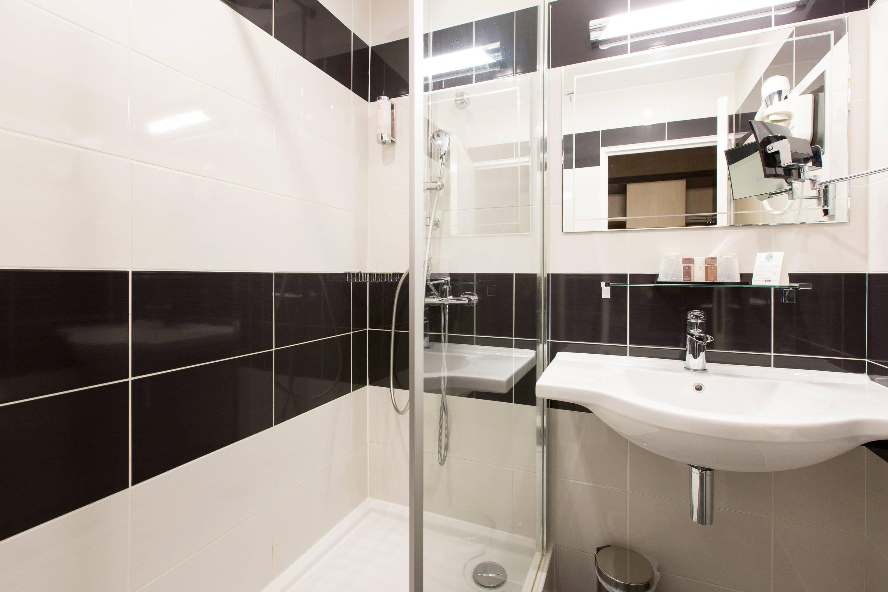 A modern bathroom with a glass-enclosed shower, a white sink, and a mirror above the sink.