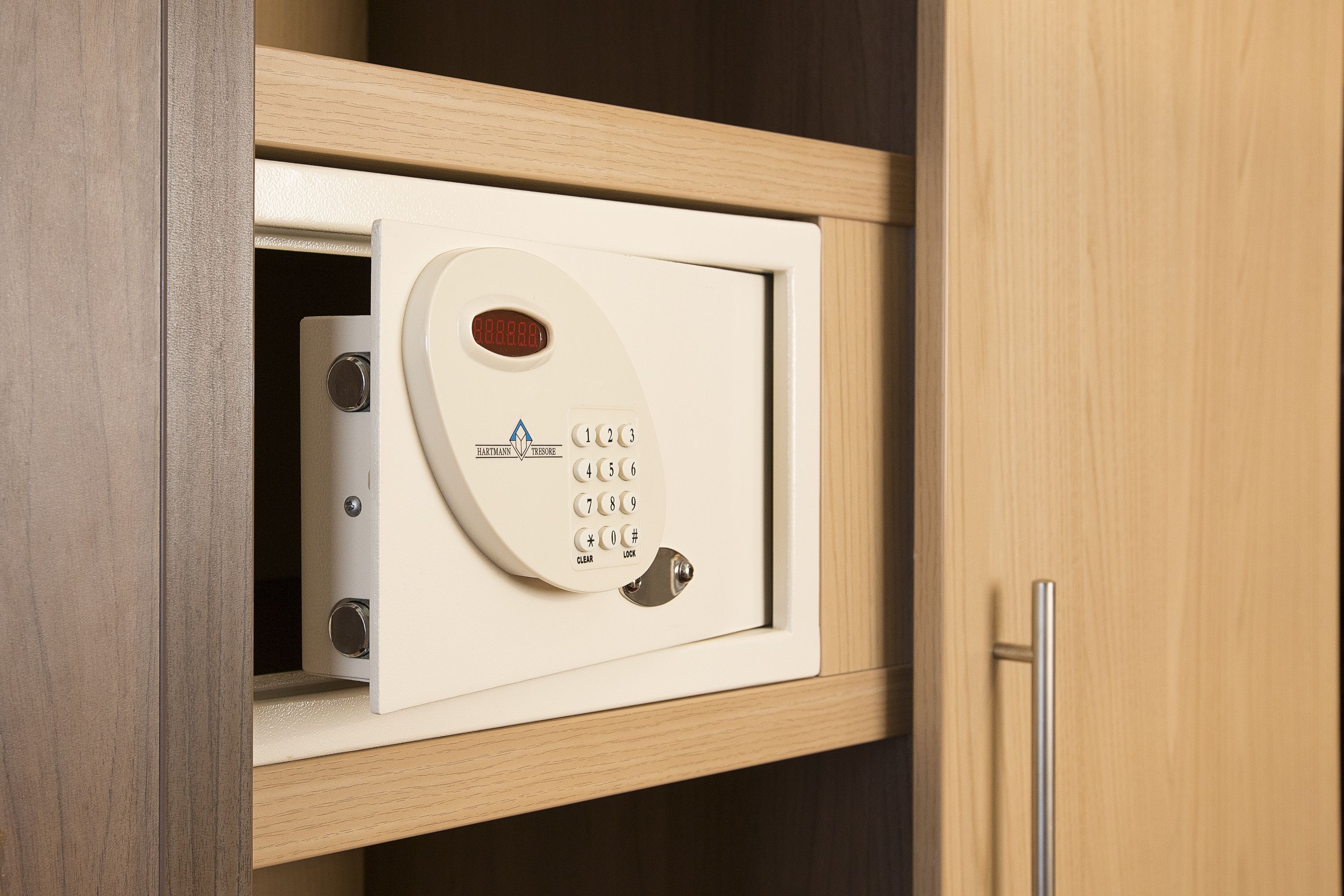 A safe with a keypad and a digital display, housed in a wooden cabinet.