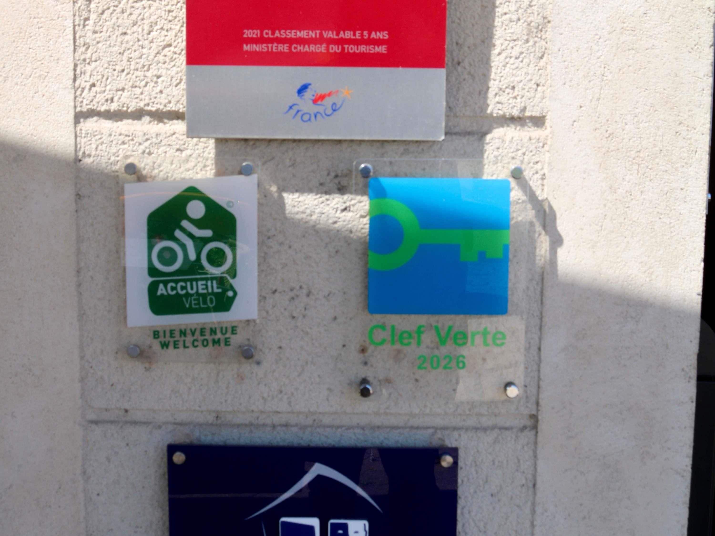 A wall with three signs: one for a cycling area, one for a welcome sign, and one for a key symbol with the year 2026.