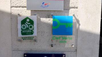 A wall with three signs: one for a cycling area, one for a welcome sign, and one for a key symbol with the year 2026.