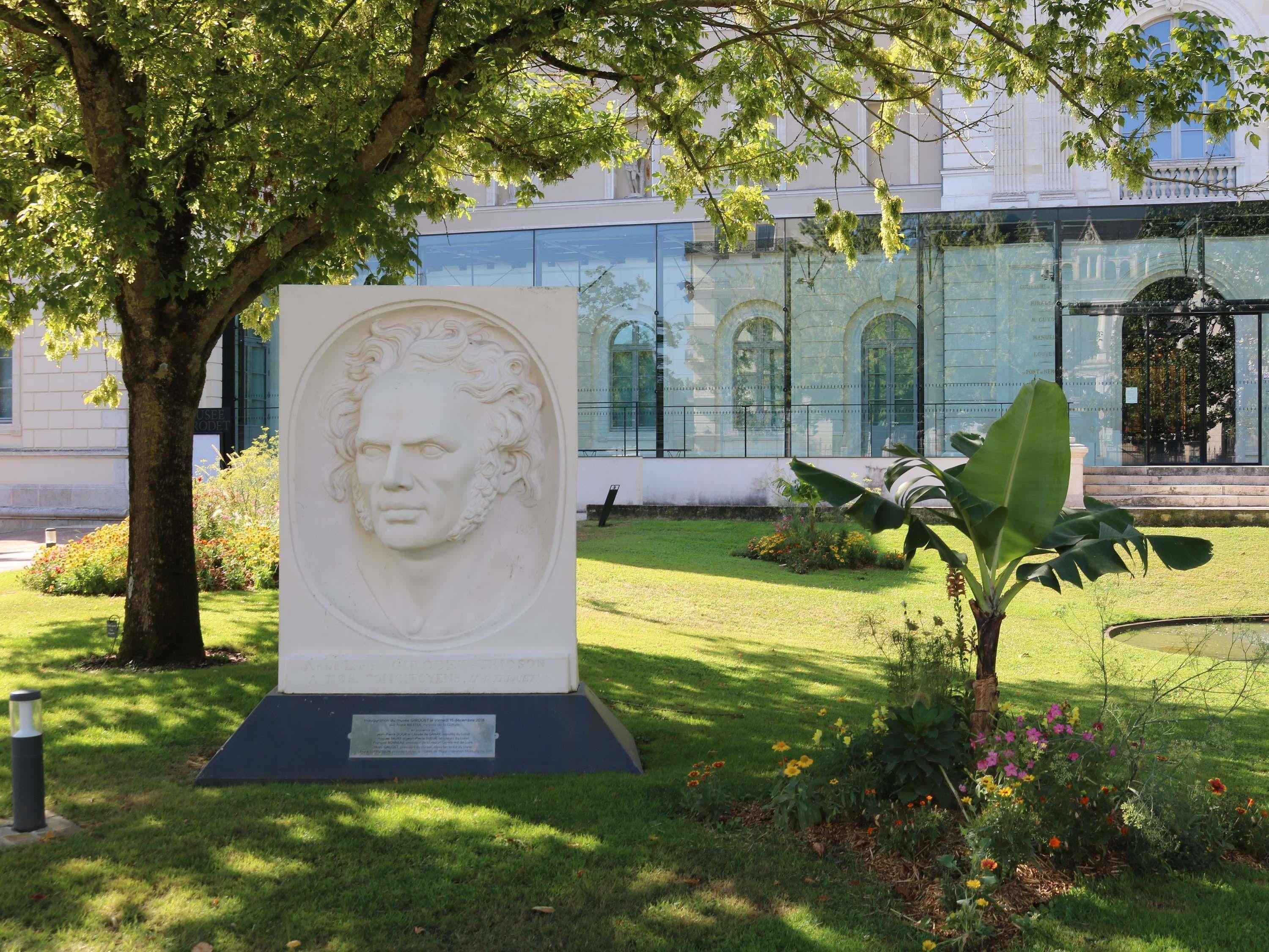 Una scultura in un giardino, con un edificio sullo sfondo.