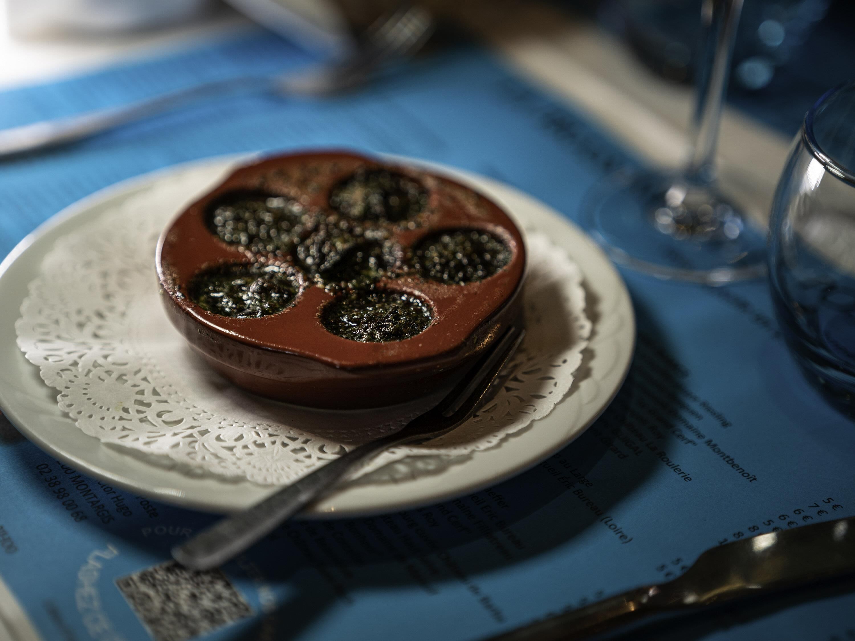 A bowl of food on a plate with a fork, placed on a table with a placemat.
