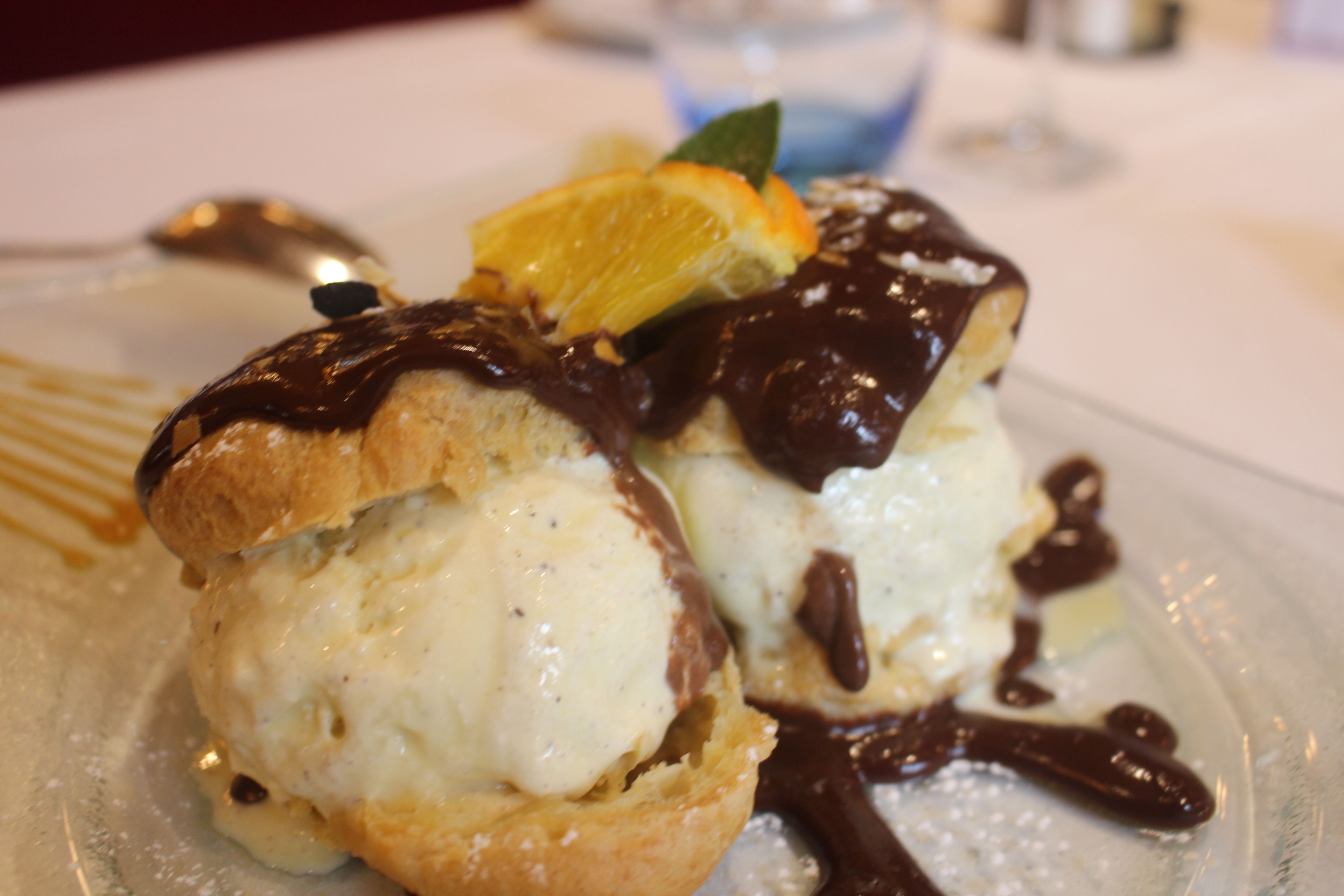 Un postre con salsa de chocolate y una rodaja de naranja en un plato.