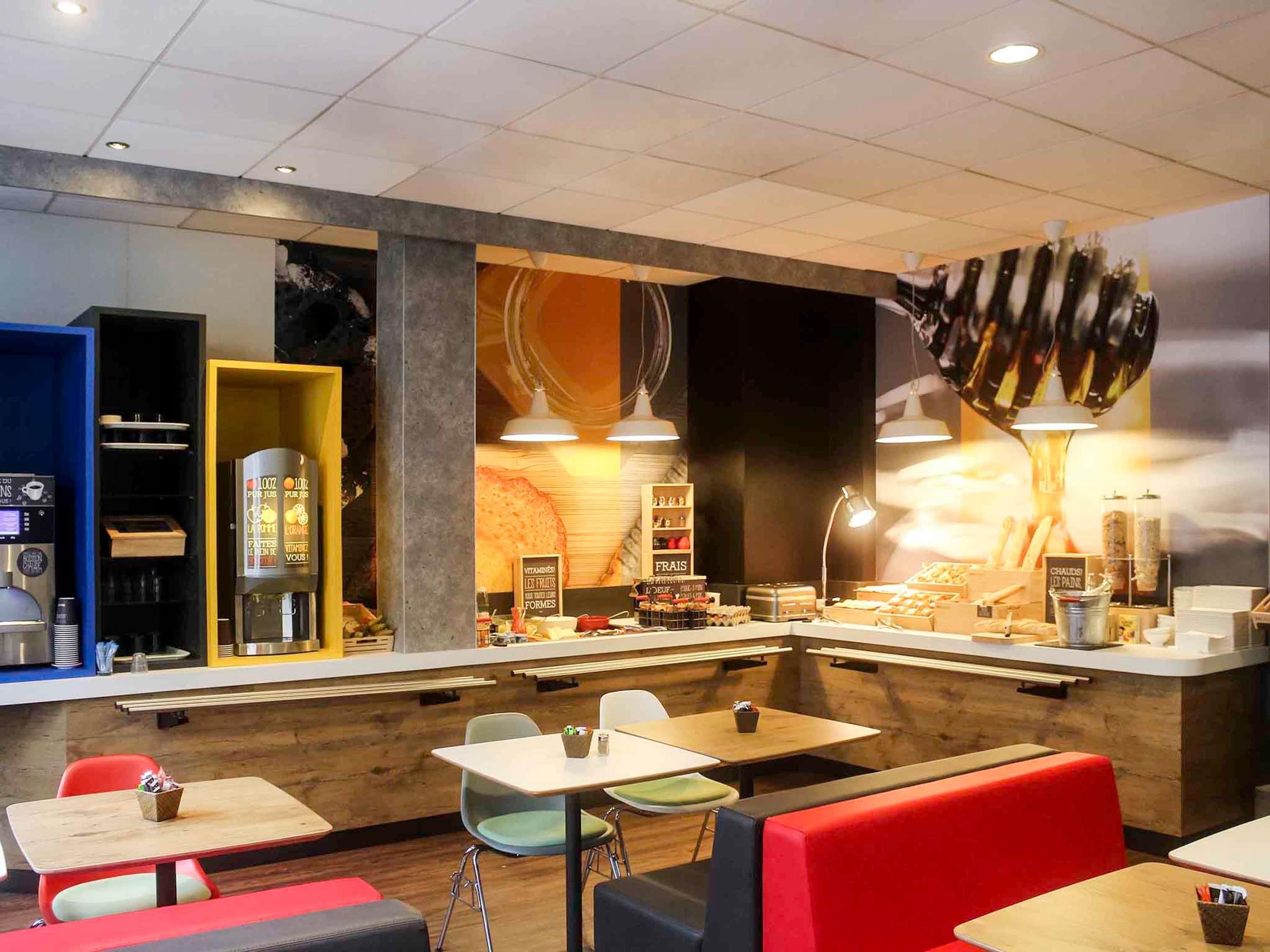 Een café-interieur met zitplaatsen, een balie en een wandgemonteerde koffieapparaat.