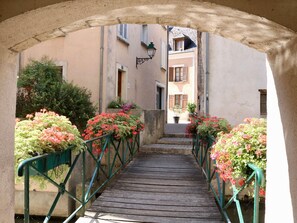 A narrow alleyway with a wooden bridge, flanked by greenery and buildings with shutters. - ibis Montargis (Montargis)
