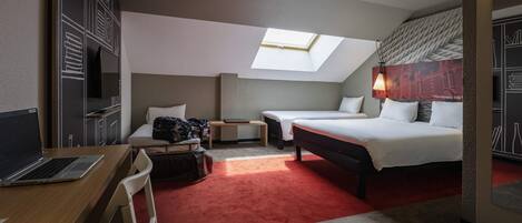 Una habitación de hotel moderna con escritorio, dos camas, tragaluz y alfombra roja.