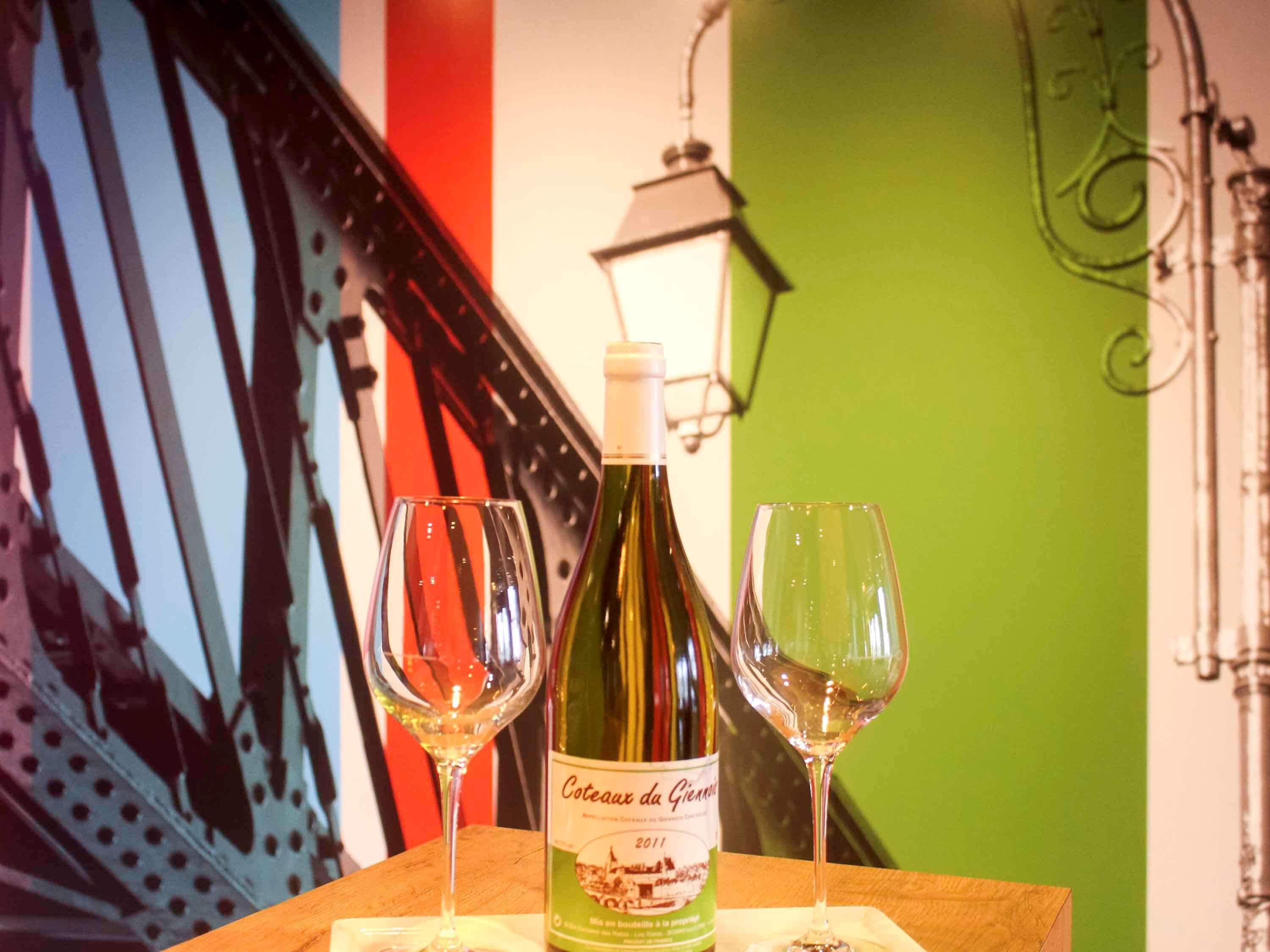 Eine Flasche Coteaux du Giennais Wein mit zwei Gläsern auf einem Holztisch.