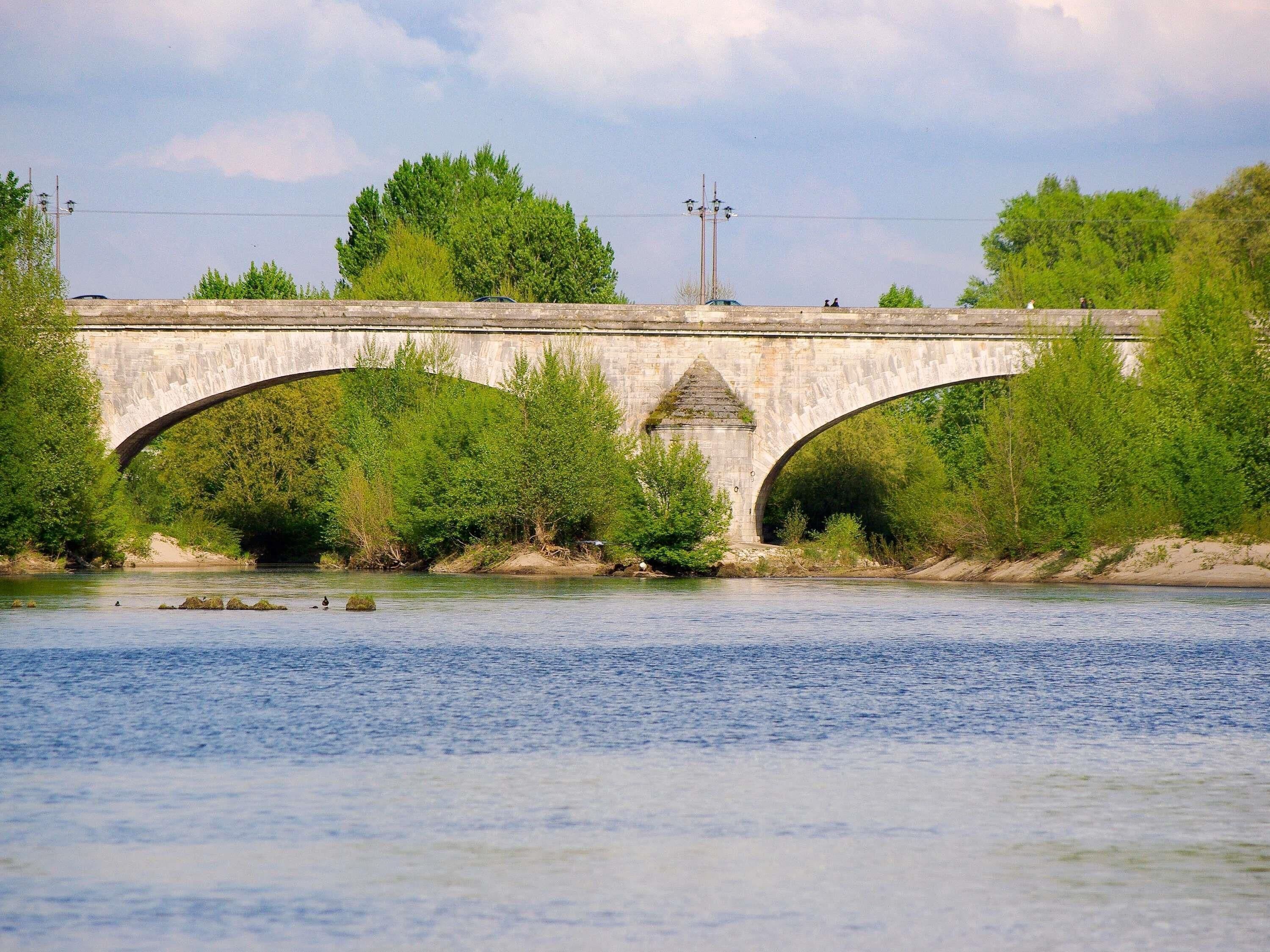 Un puente de piedra sobre un río, flanqueado por vegetación a ambos lados.