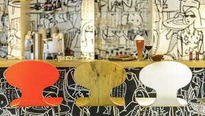 A bar area with a graffiti wall, a wooden bar counter, and hanging pendant lights. - ibis Orléans Centre Gare (Orléans)