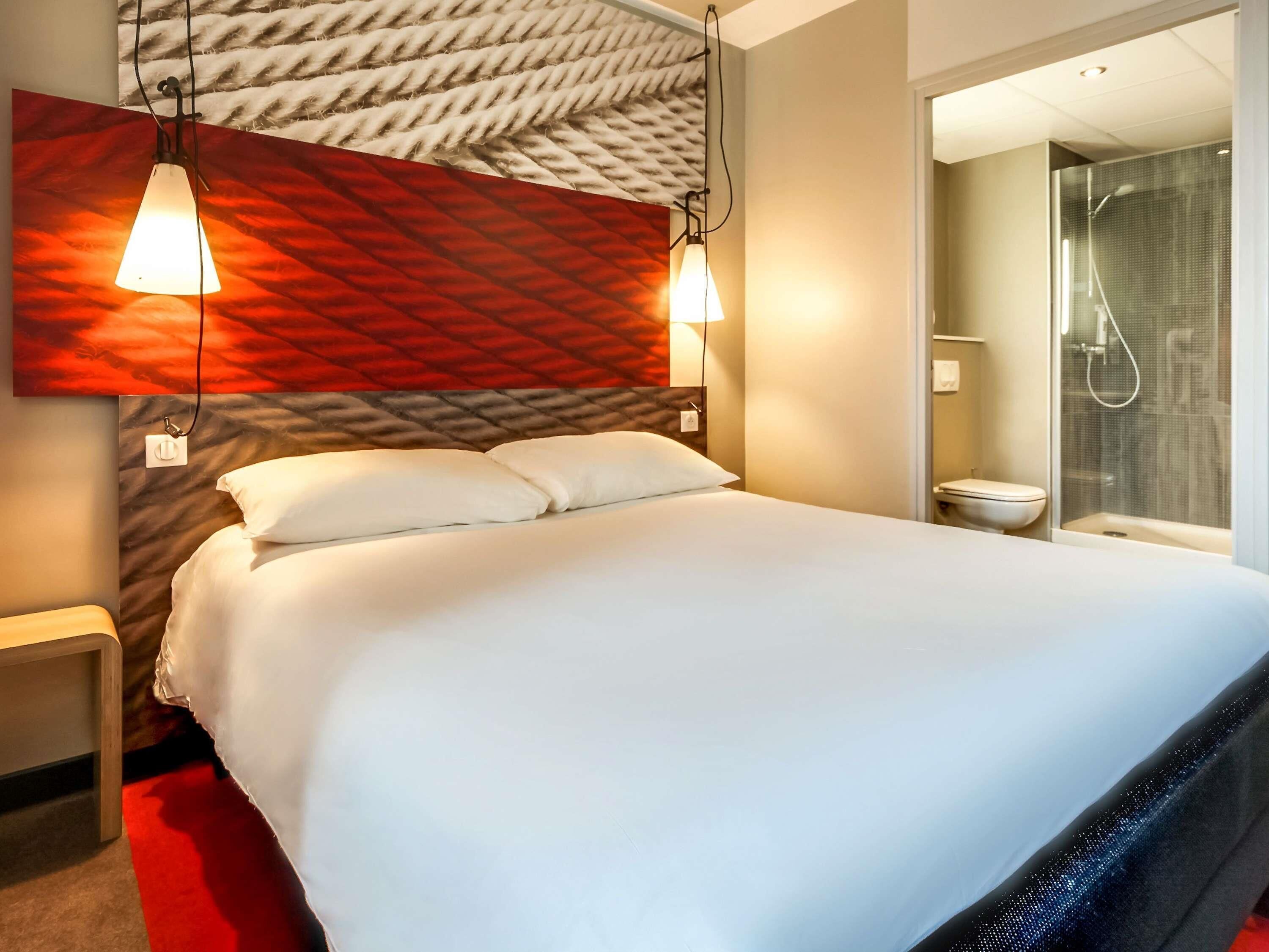 Une chambre d’hôtel comprenant un lit, des tables de chevet, un espace douche et un mur à texture.