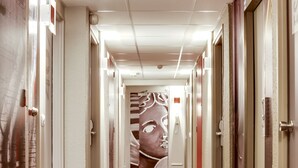 A hotel corridor with patterned carpet, doors, and a large mural on the wall. - ibis Orléans Centre Gare (Orléans)