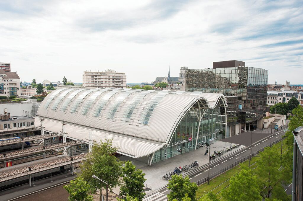 Una estación de tren moderna con un techo grande y curvo y varias vías.