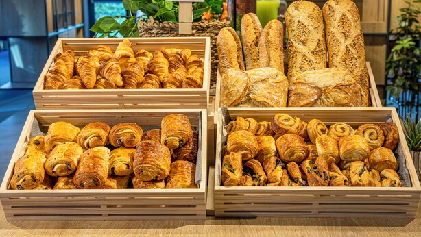 A display of various baked goods in wooden crates, including croissants and baguettes. - ibis Orléans Centre Gare (Orléans)