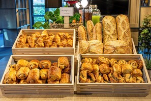 Una exhibición de diversos productos horneados en cajas de madera, incluyendo croissants y barras de pan.