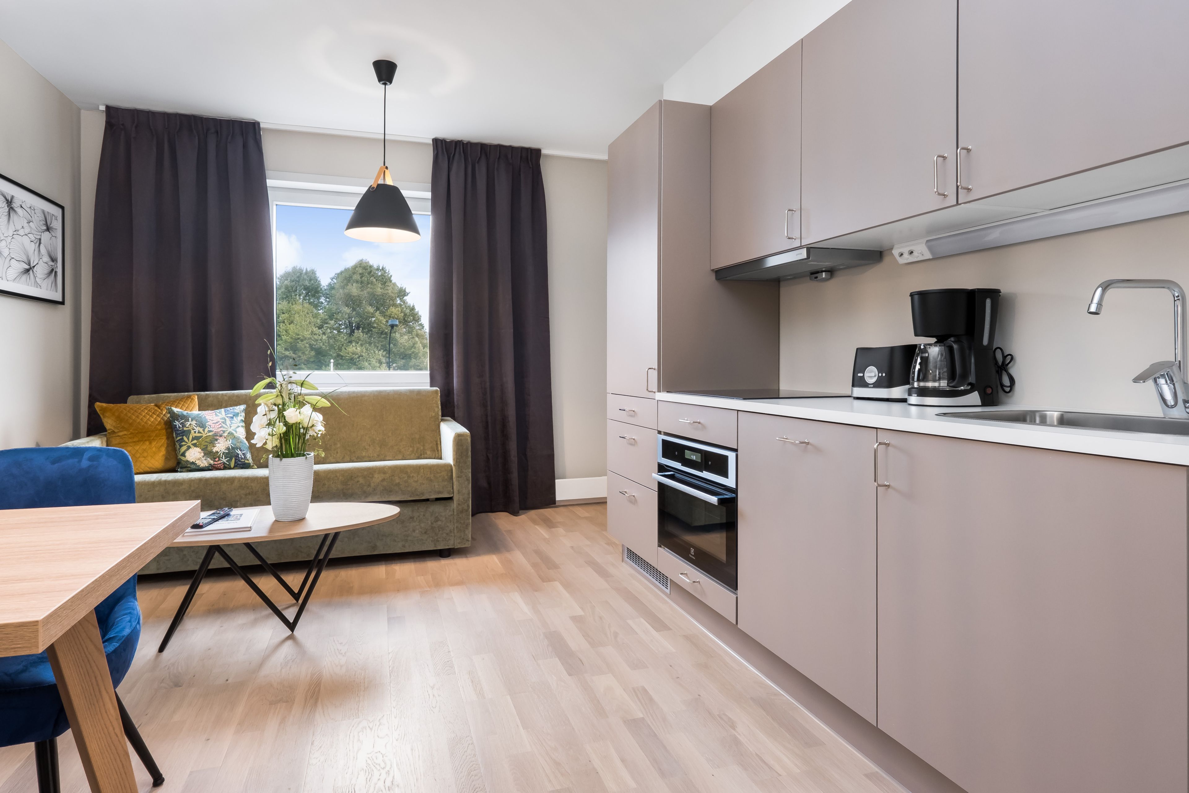 Una cocina moderna con zona de comedor, sofá y ventana con cortinas.