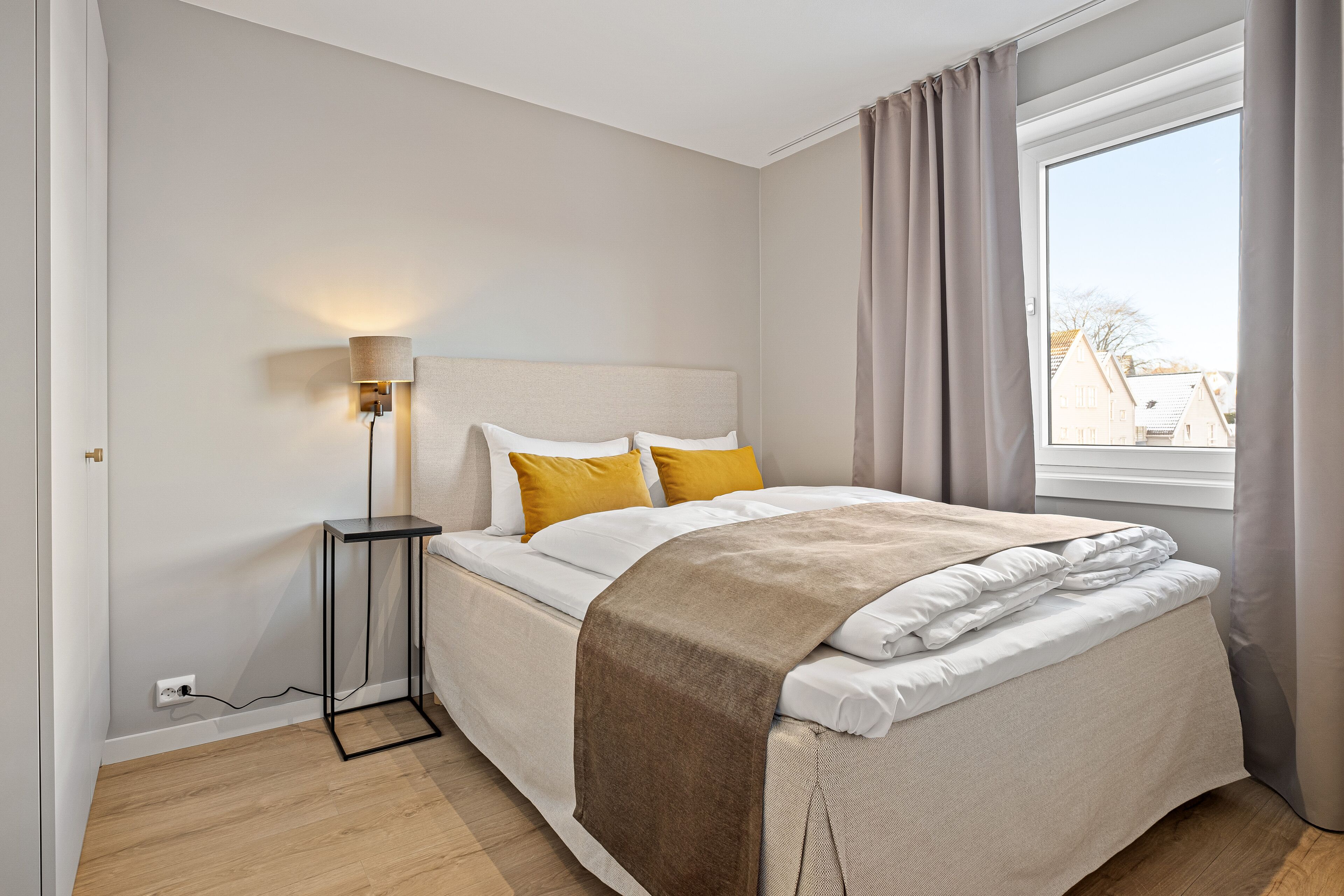 A bedroom with a bed, bedside lamp, and a window with curtains.