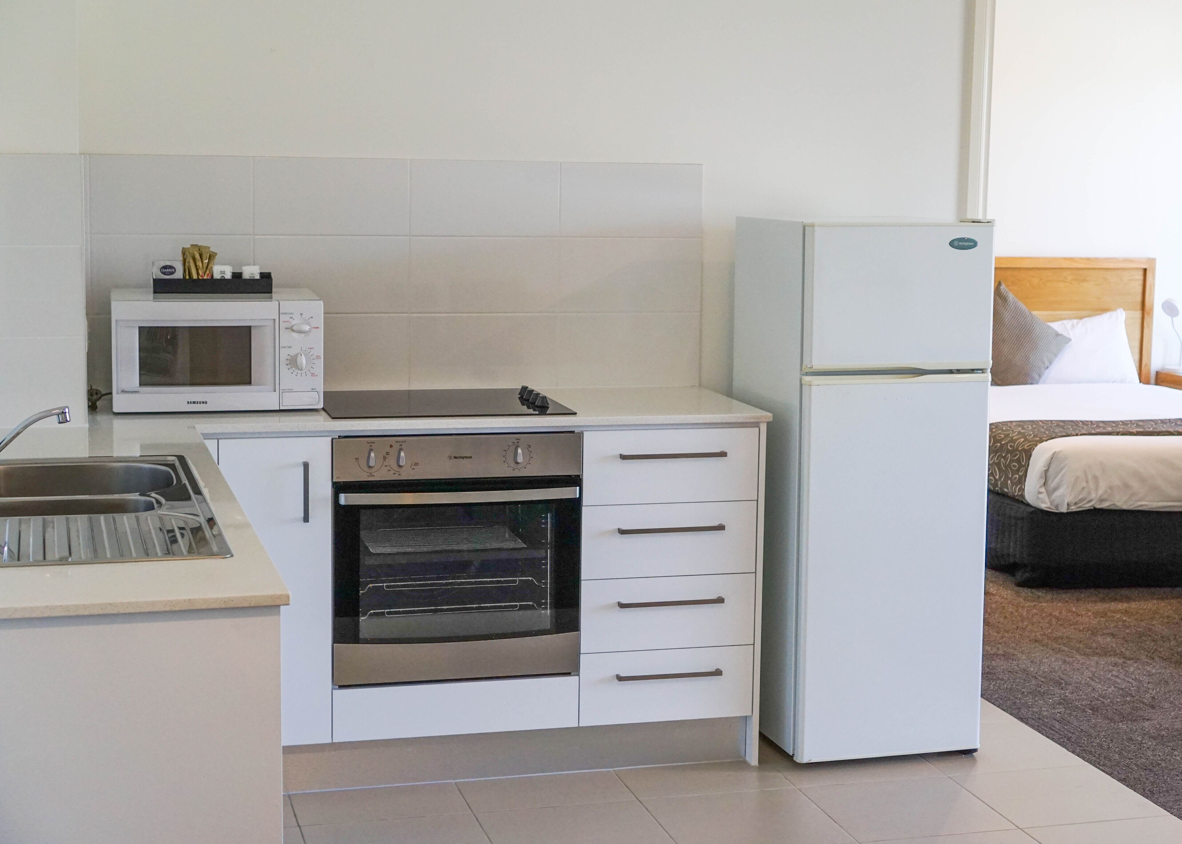 Eine kleine Küchenzeile mit Mikrowelle, Backofen und Kühlschrank.