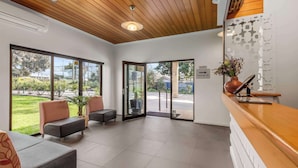 A reception area with a wooden ceiling, large windows, and a reception desk with a vase of flowers. - Best Western Geelong Motor Inn & Serviced Apartments (Geelong)