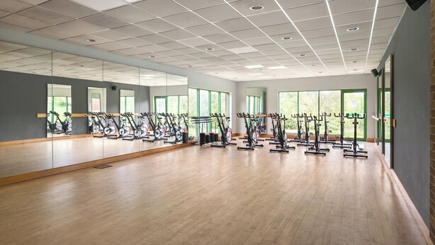 A spacious gym with multiple exercise bikes, large windows, and a wooden floor. - Holiday Inn Birmingham M6 Jct7 by IHG (Birmingham)