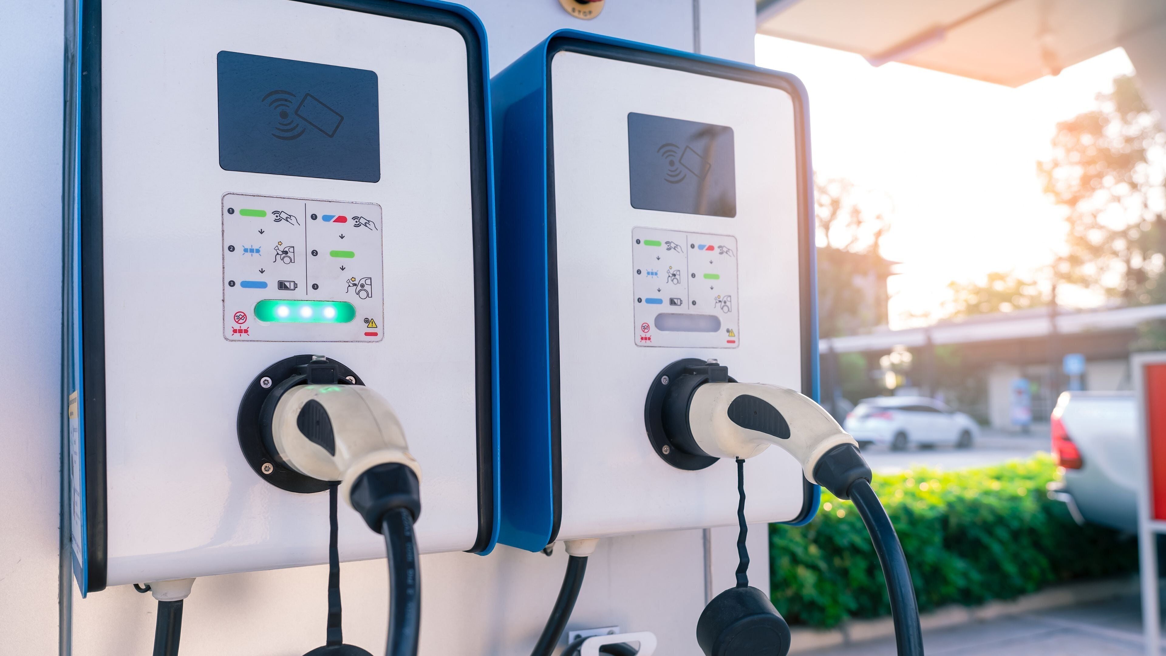 Two electric vehicle charging stations with control panels and charging cables.