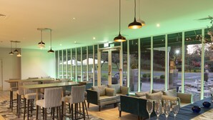 A modern indoor dining area with a bar, seating, and large windows.