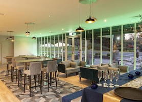 Un espace de restauration intérieur moderne, doté d’un bar, de sièges et de grandes fenêtres.
