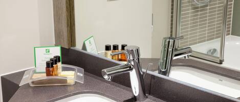 A modern bathroom with a dual sink, a large mirror, and a shower area.