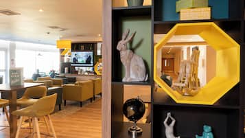 A modern interior with a wooden floor, seating area, and a wall with decorative items including a globe and sculptures.