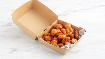 A cardboard box with a white interior containing a food item.
