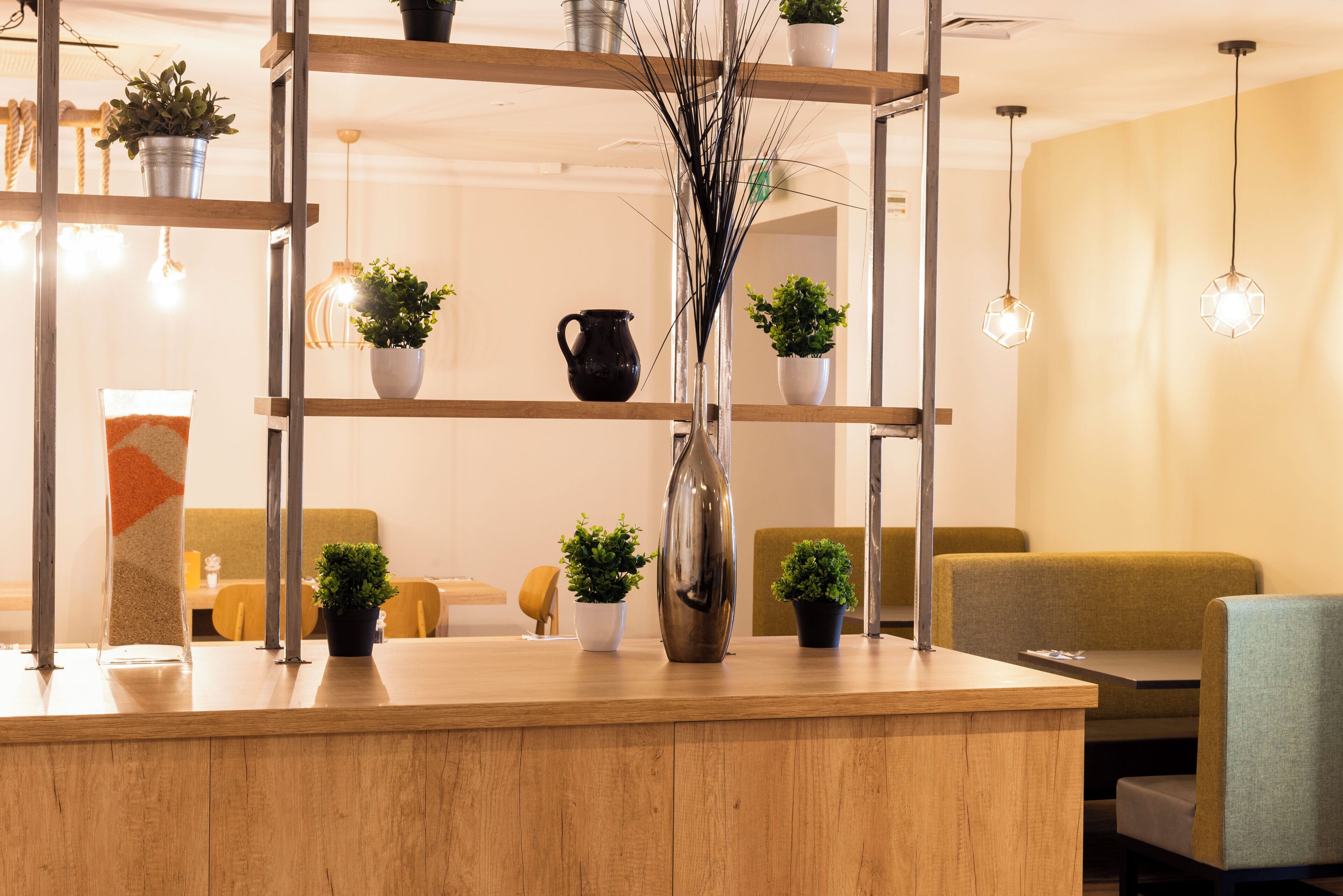 A reception area with a wooden reception desk, multiple potted plants, and a seating area with sofas.