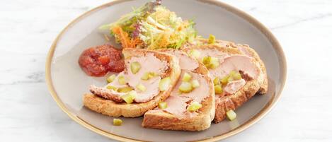 A plate with sliced meat, a salad, and a small portion of sauce.