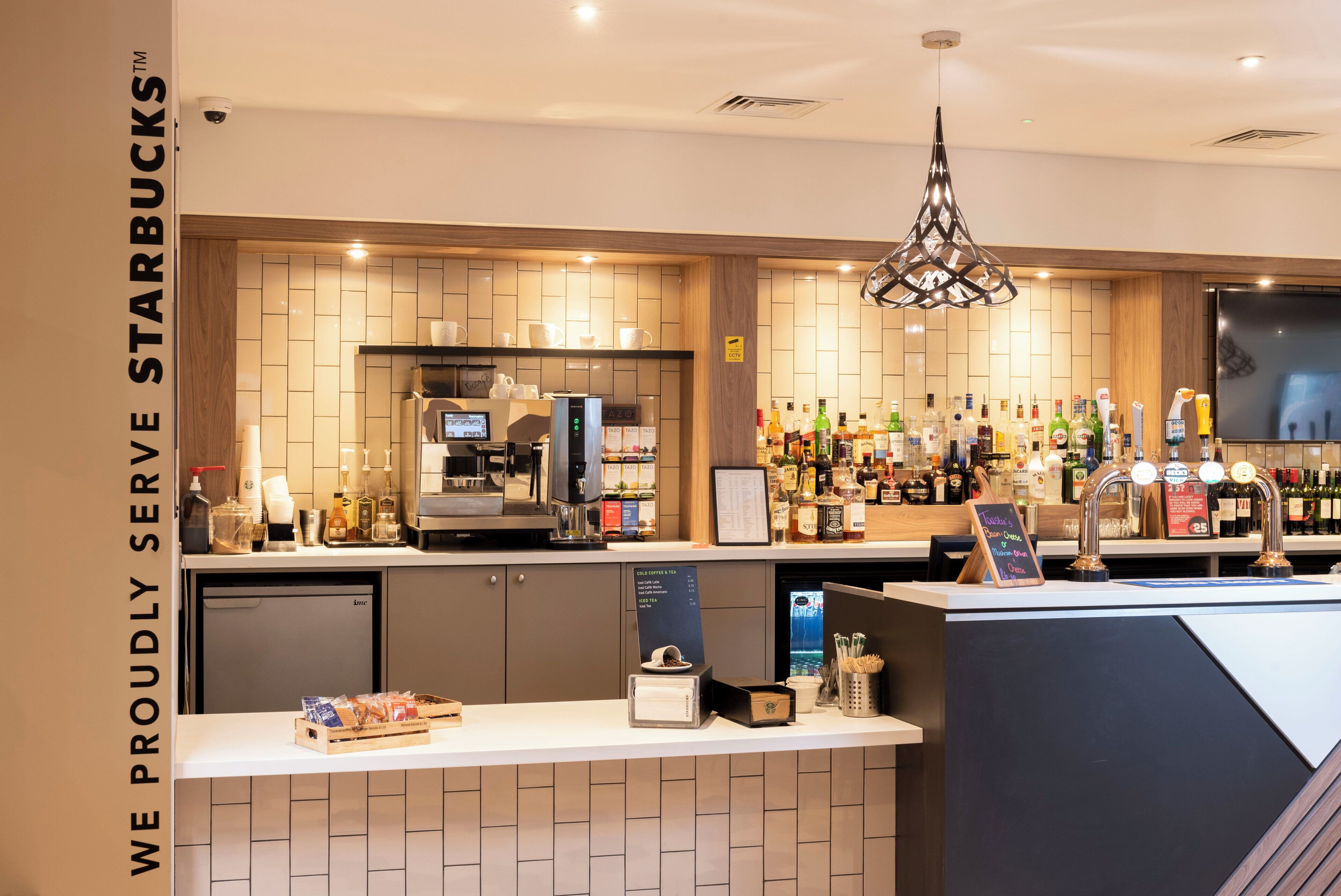 A Starbucks counter with a coffee machine, a selection of beverages, and a variety of coffee beans displayed.