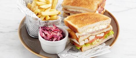 Un plato con un sándwich, papas fritas y ensalada de col.