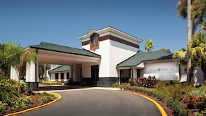 A hotel entrance with a covered driveway, palm trees, and a sign reading "Four Points by Sheraton".