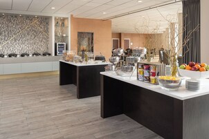 Een moderne ontbijtruimte met buffettafels, diverse soorten eten en een decoratieve muur.
