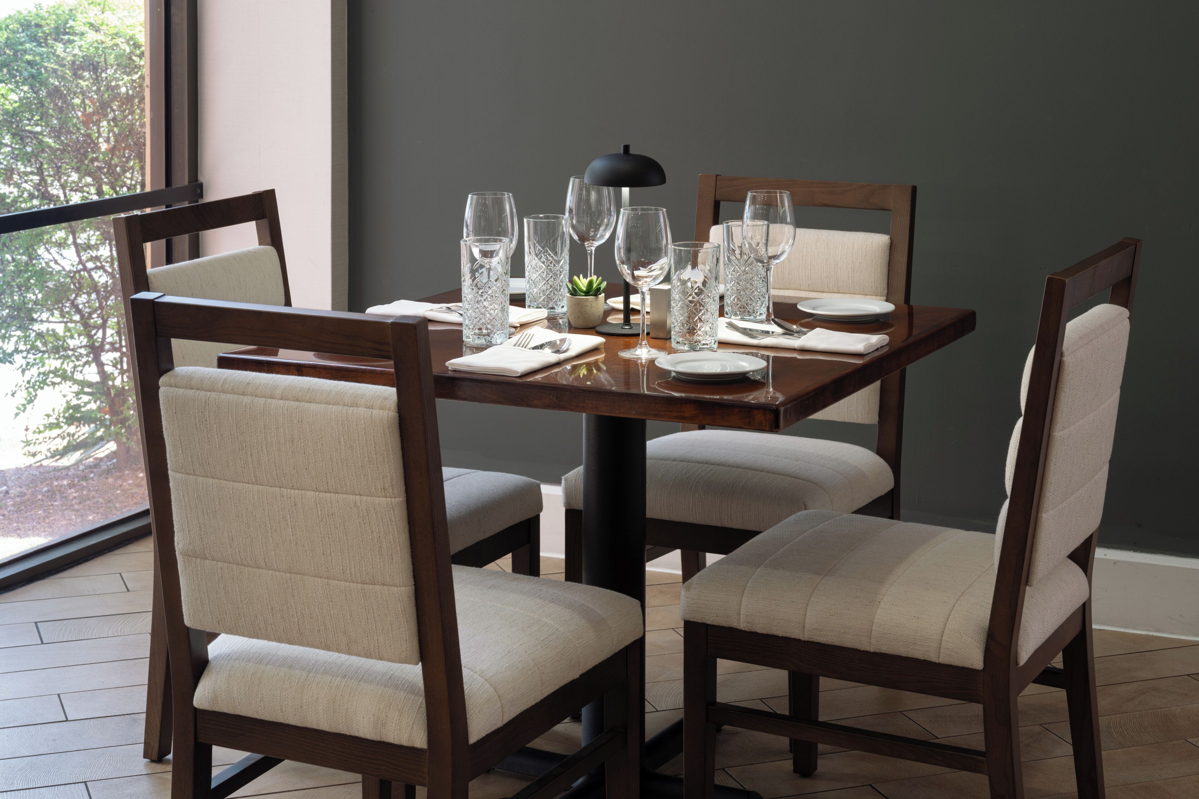Una mesa de comedor con sillas, una lámpara y cristalería.