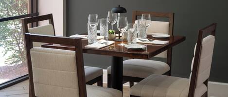 Una mesa de comedor con sillas, una lámpara y cristalería.
