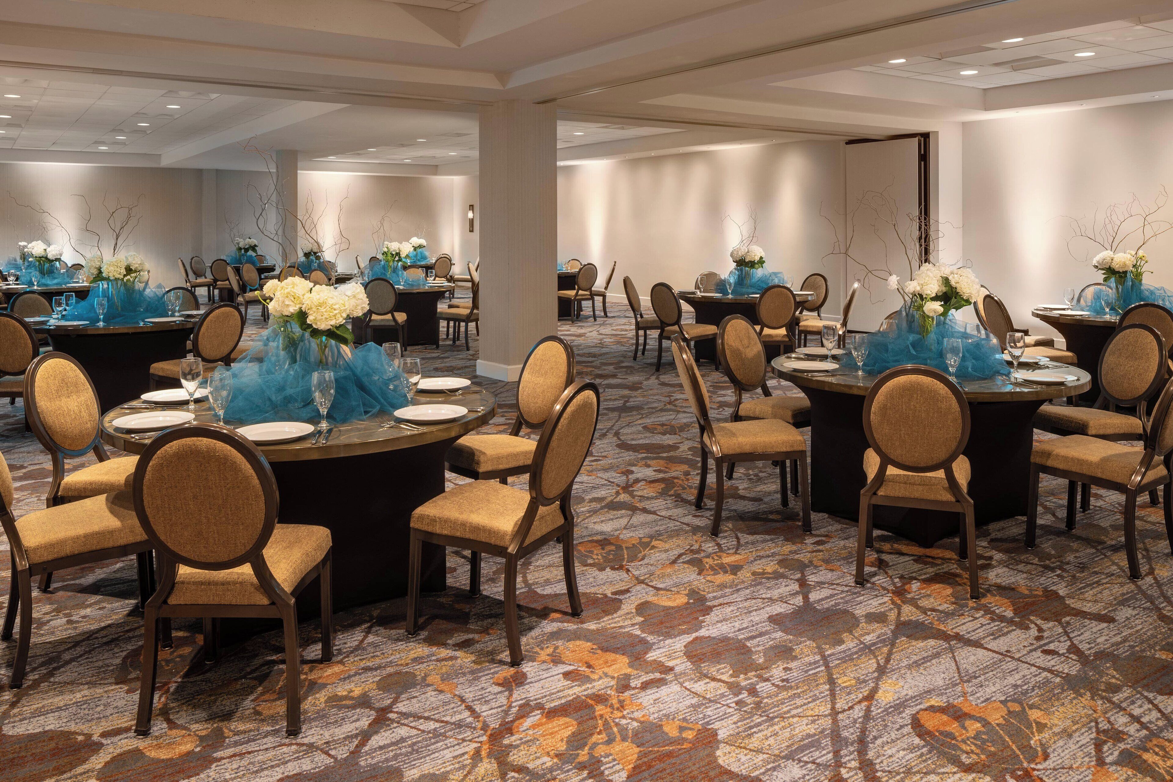 A conference room with round tables, chairs, and floral centerpieces.