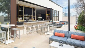 An outdoor seating area with a bar, tables, and sofas.