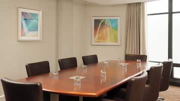 A conference room with a long table, eight chairs, and two framed abstract paintings on the walls.