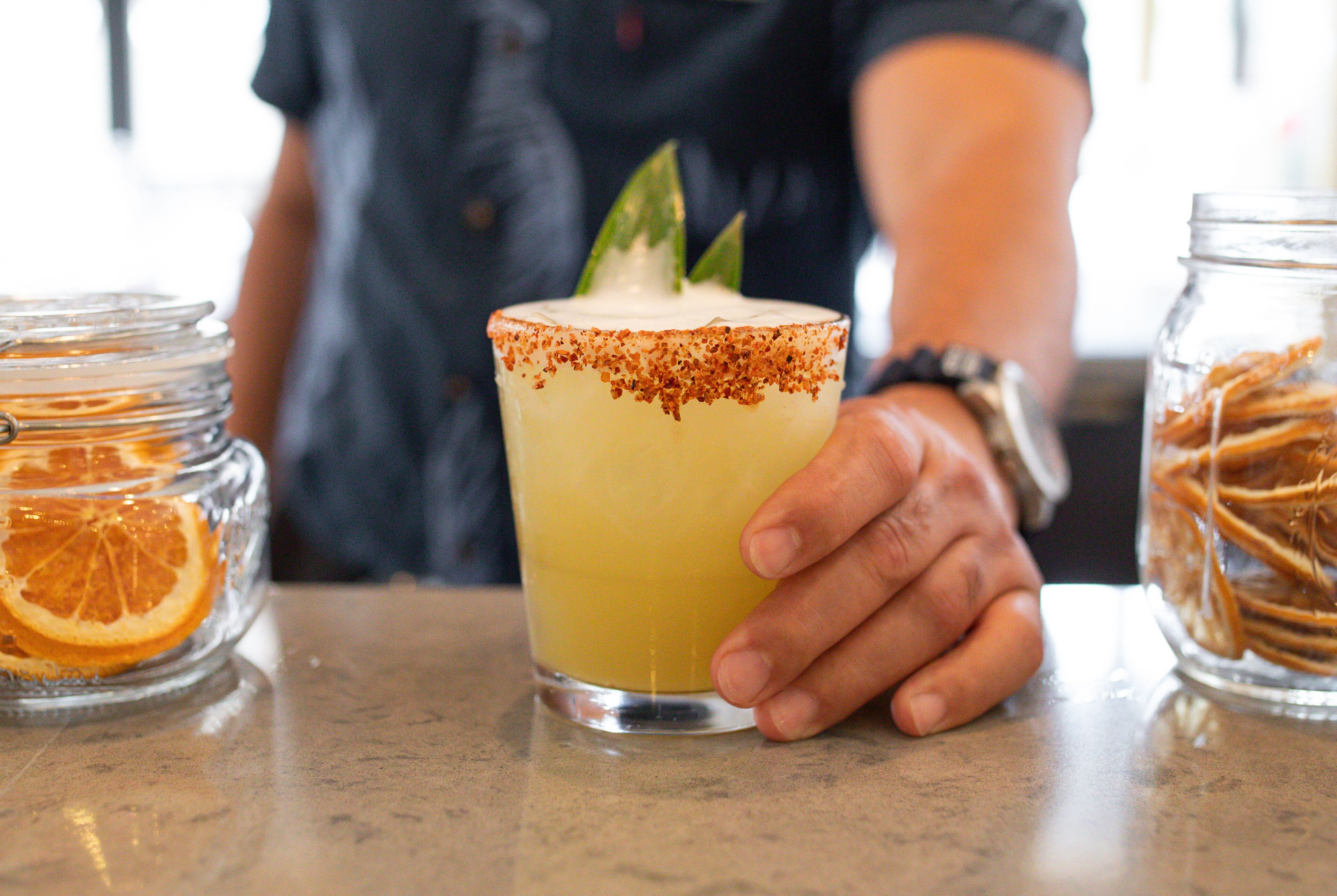 Een hand die een margarita vasthoudt, met een zoutrandje en een limoen.