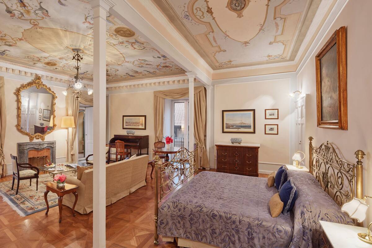 Un dormitorio lujoso con una cama grande, un espejo elegante y un piano.