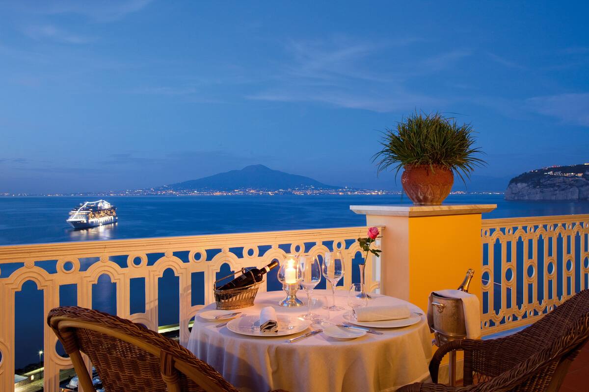 Una mesa para dos con vista al mar y una montaña distante.