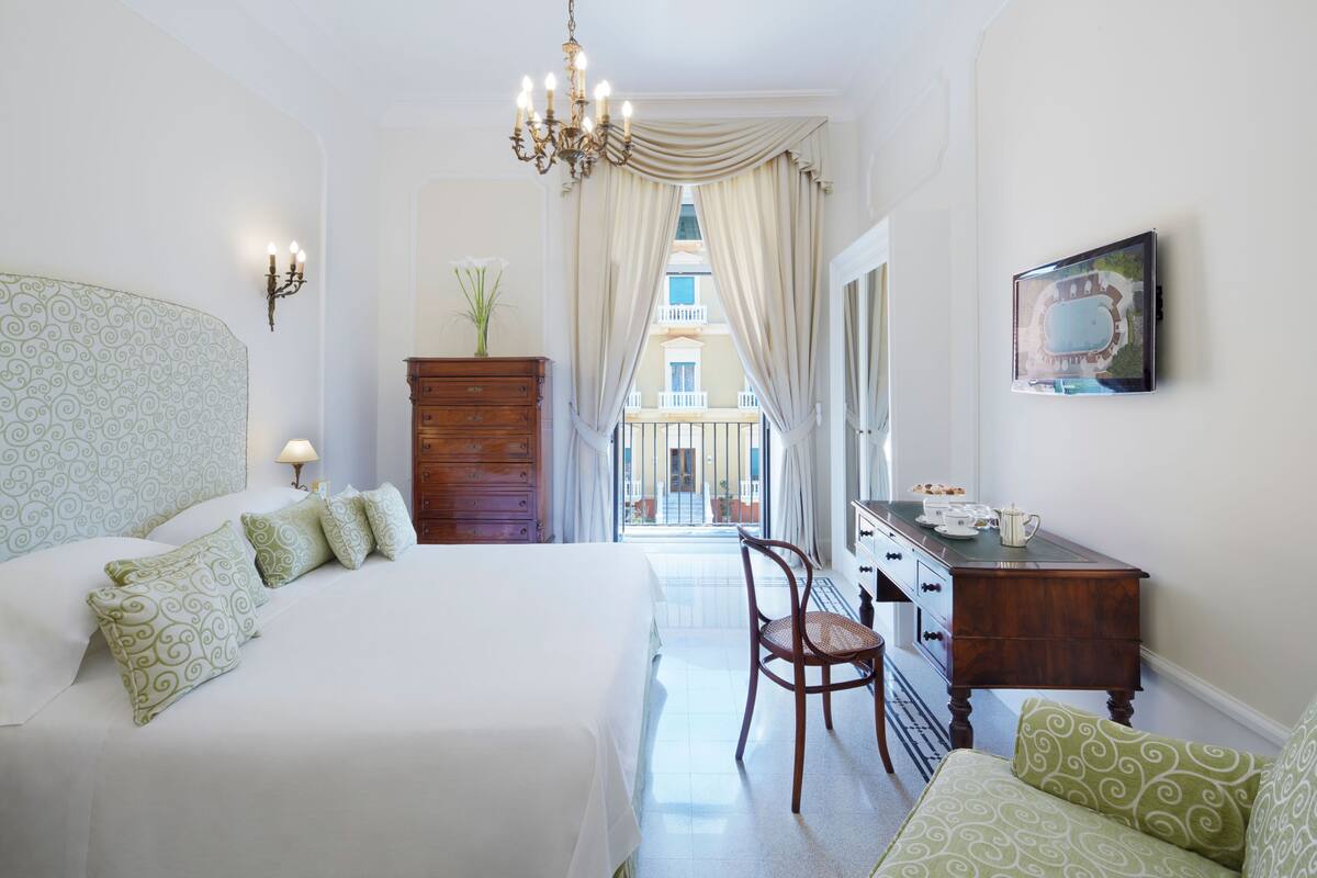 Habitación de hotel con una cama grande, un aparador de madera, una silla y un escritorio con televisor de pantalla plana.