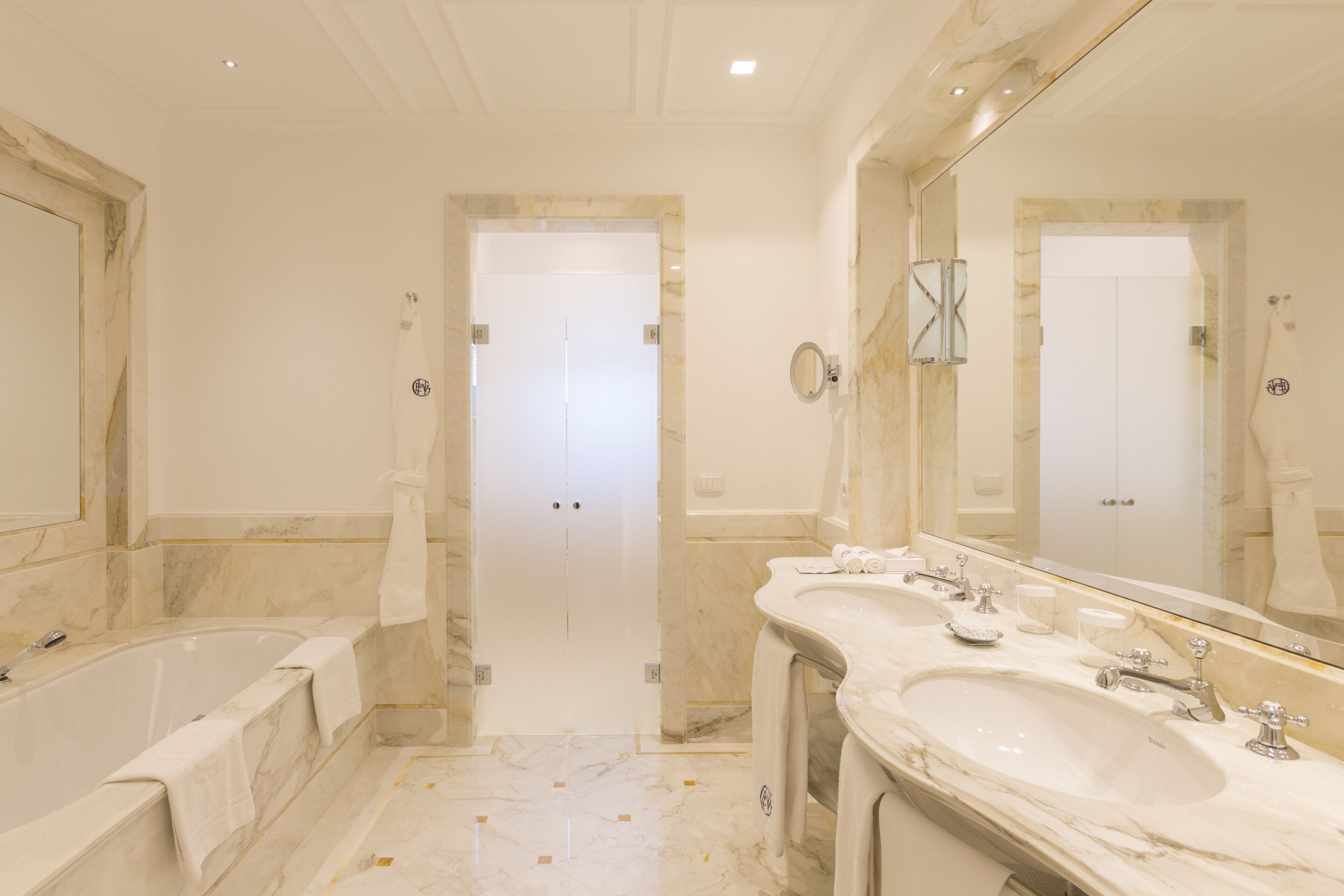 A luxurious bathroom with a large bathtub, two sinks, and a mirror.
